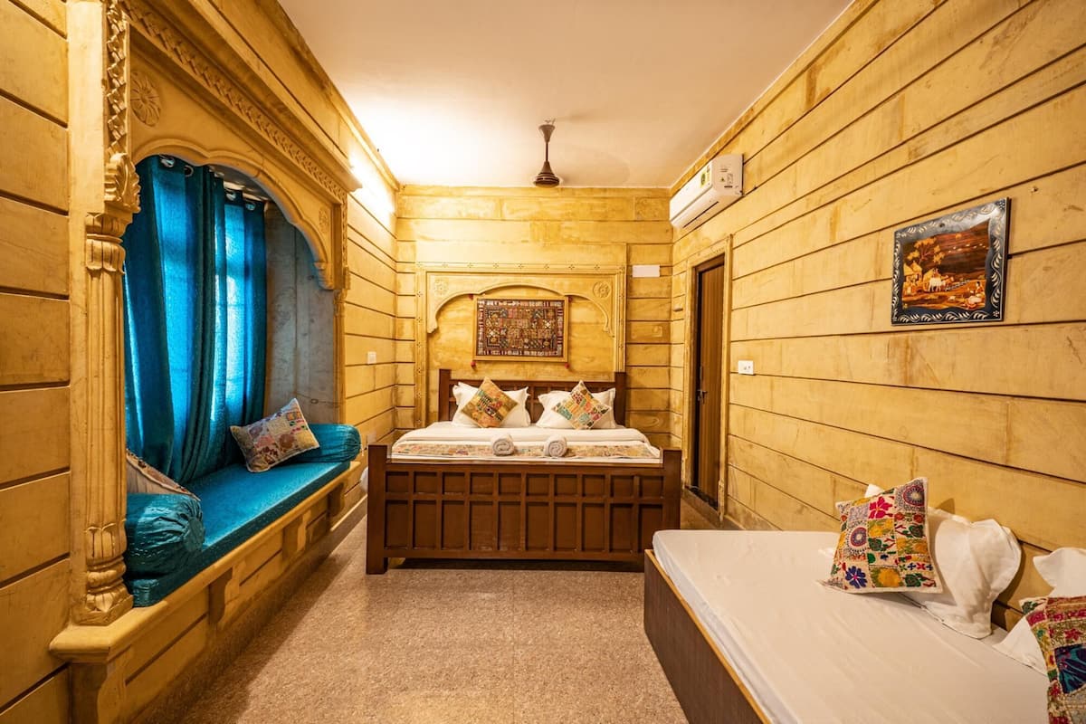 A narrow room with a bed, a bench, and a wall with a picture.