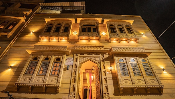 Um edifício tradicional com detalhes arquitetônicos ornamentados, incluindo várias janelas com desenhos elaborados e uma placa indicando que é um hotel.