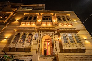 Ein traditionelles Gebäude mit aufwendigen architektonischen Details, darunter mehrere Fenster mit filigranen Verzierungen und ein Schild, das es als Hotel kennzeichnet.
