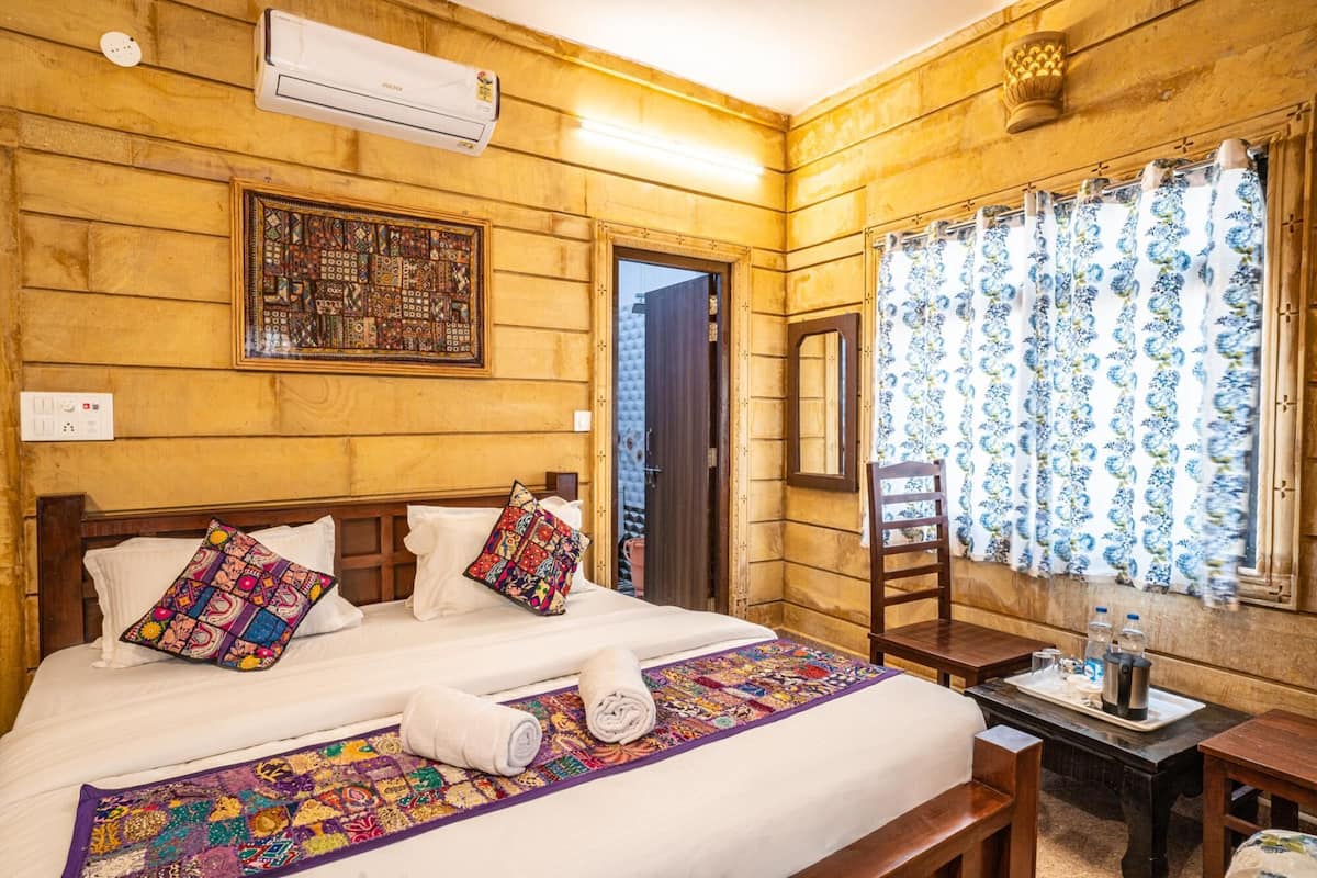 A wooden room with a bed, a desk, and a window with curtains.