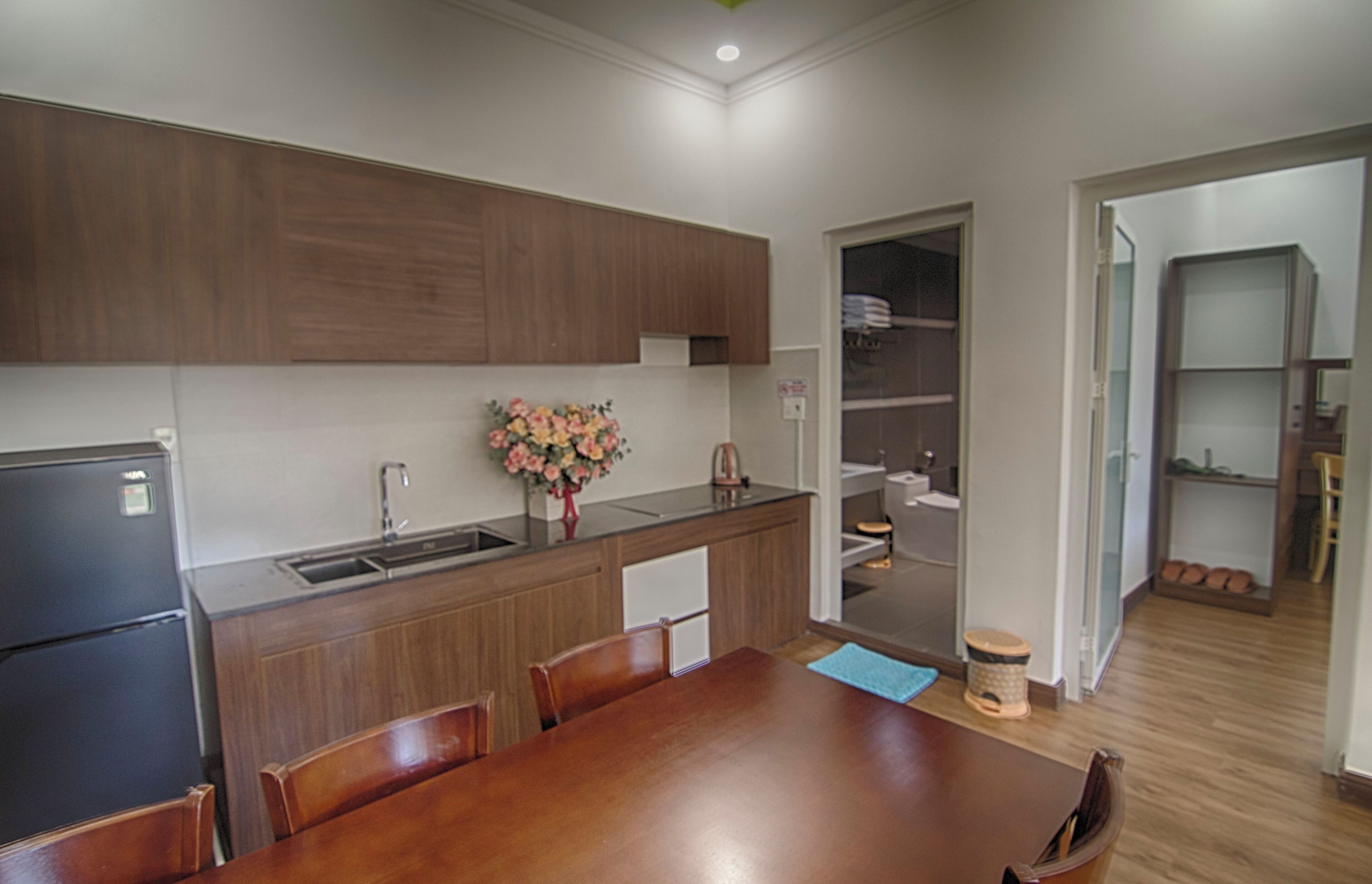 A modern kitchen with wooden cabinets, a built-in sink, and a dining area with a wooden table and chairs.