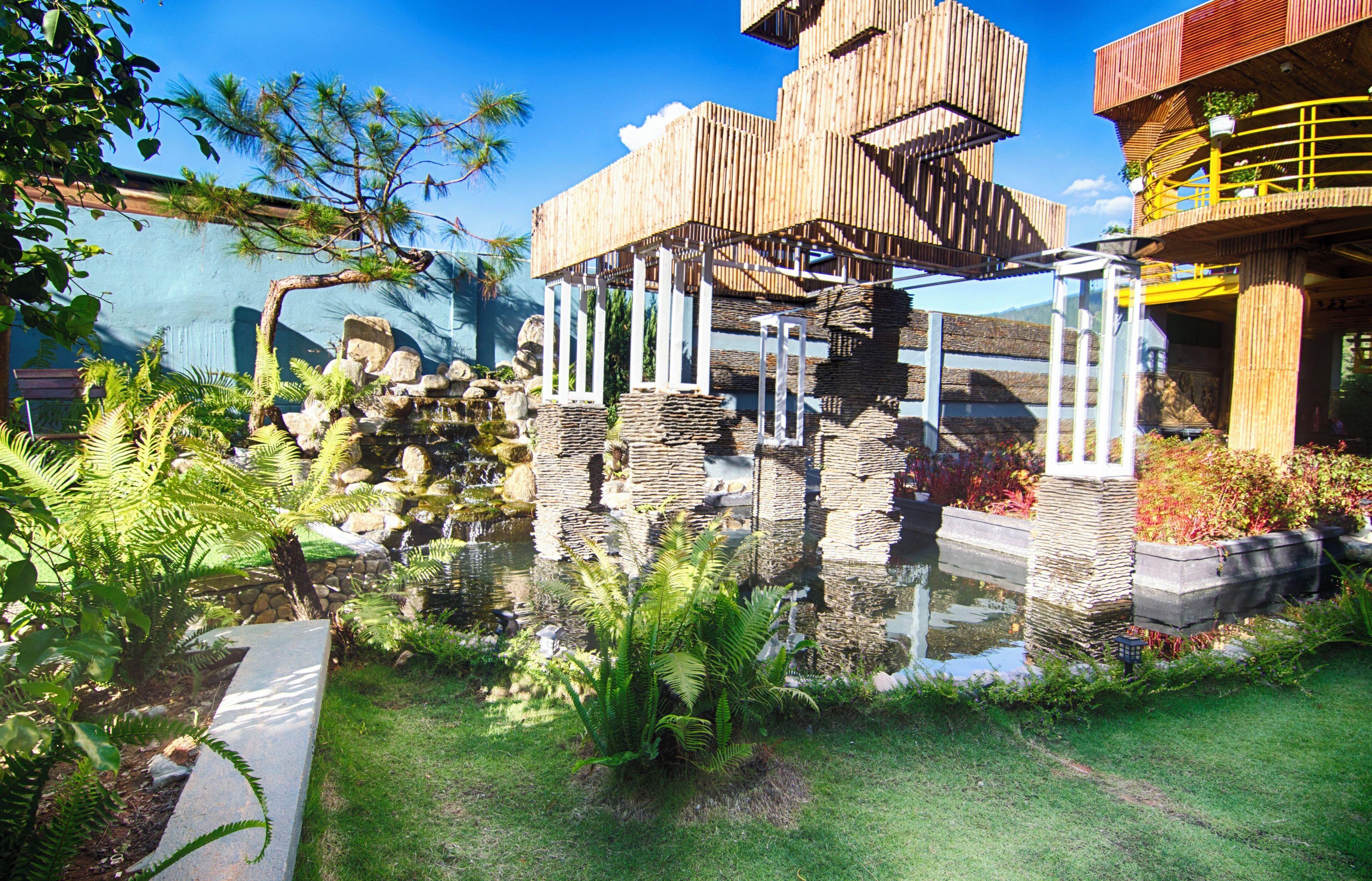 A modern building with a unique wooden structure, a pond, and lush greenery.