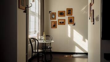 Un comedor con una mesa y sillas, una ventana con persianas y cuadros en la pared.