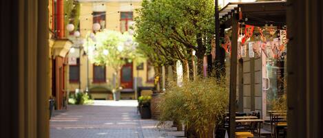 A narrow street lined with buildings, outdoor seating, and hanging lanterns.