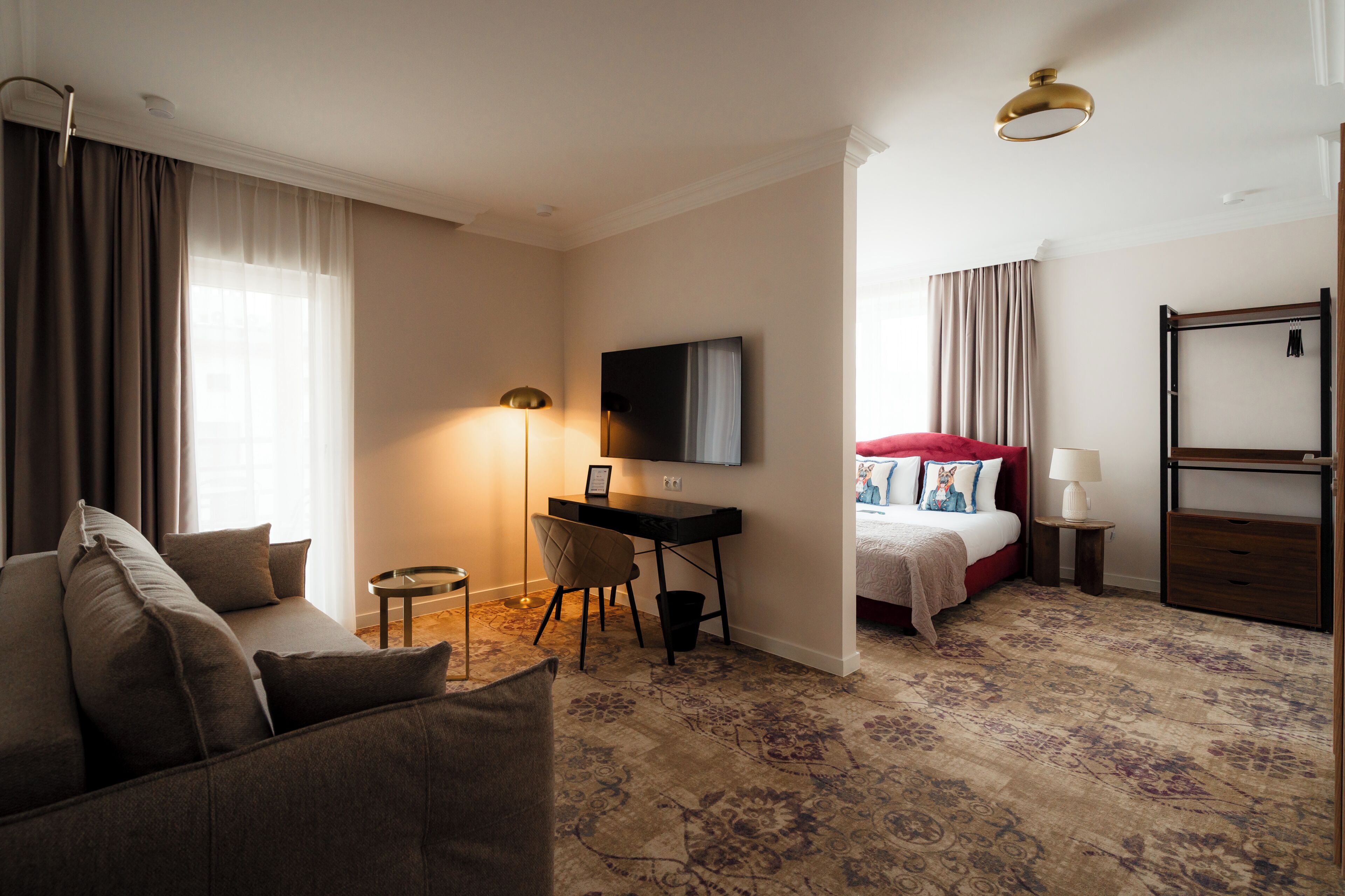 Habitación de hotel con sofá, escritorio, cama, televisor y lámpara.