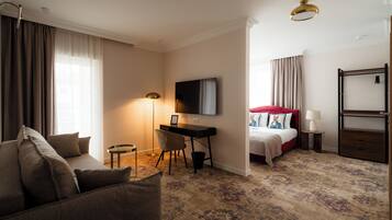 Habitación de hotel con sofá, escritorio, cama, televisor y lámpara.