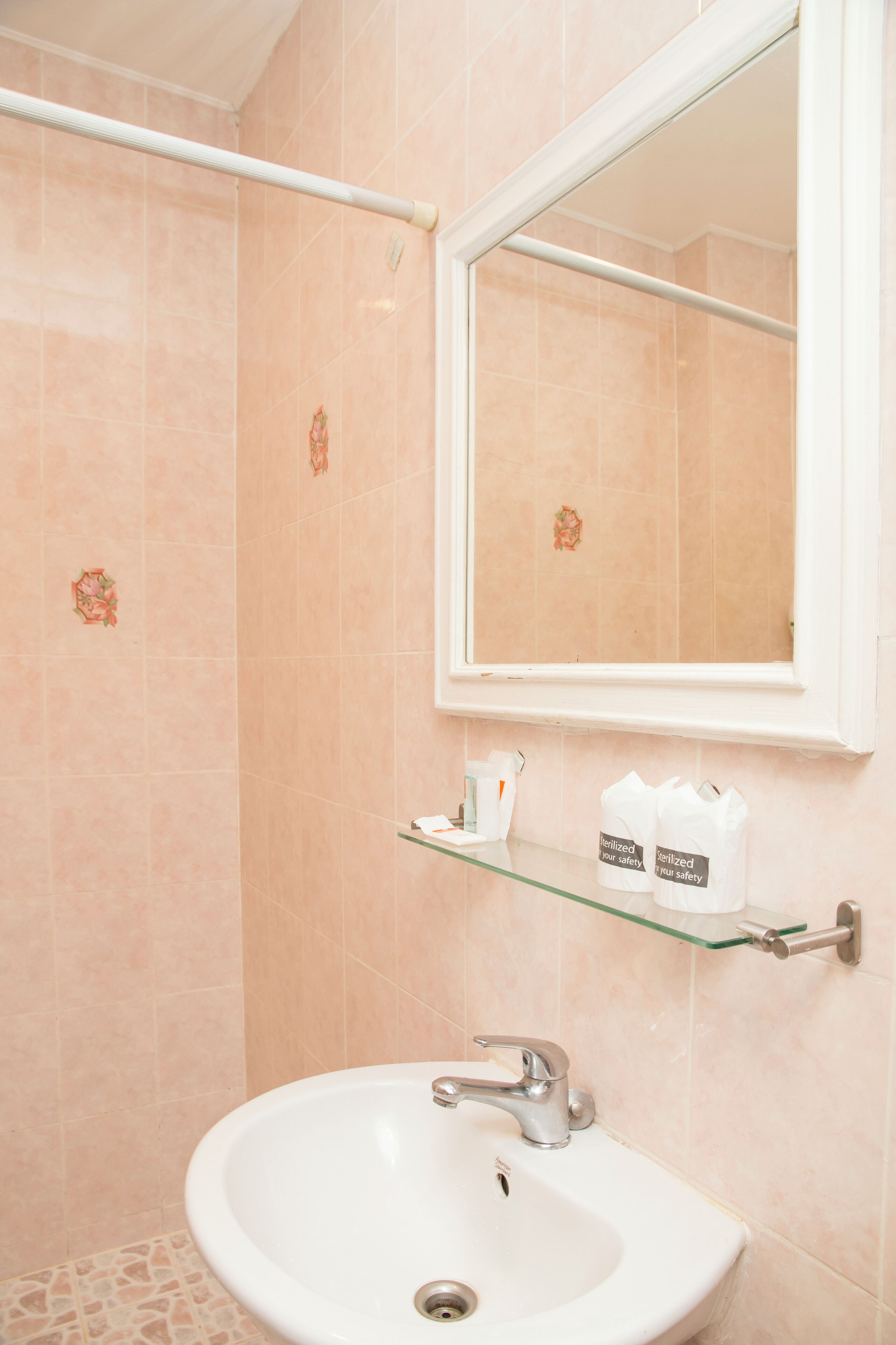 A bathroom with a white sink, a mirror, and a glass shelf with toiletries.