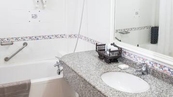 A bathroom with a granite countertop, a white sink, a bathtub, a shower, and a mirror.