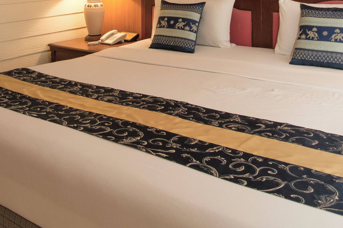 Une chambre d’hôtel avec un lit bien fait, une lampe de chevet, un téléphone et un tableau au mur.