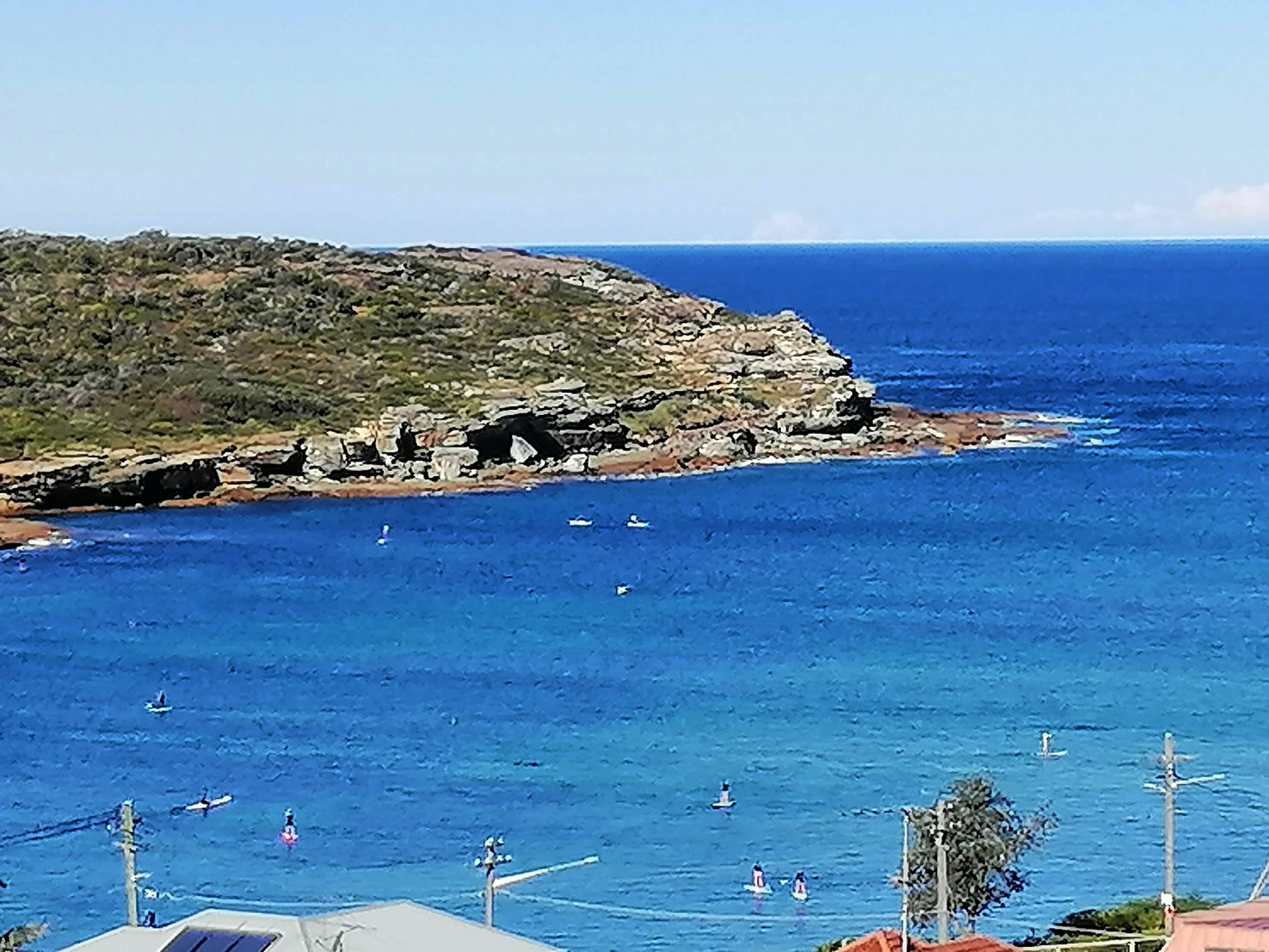 A coastal view with rocky terrain and clear blue sea.