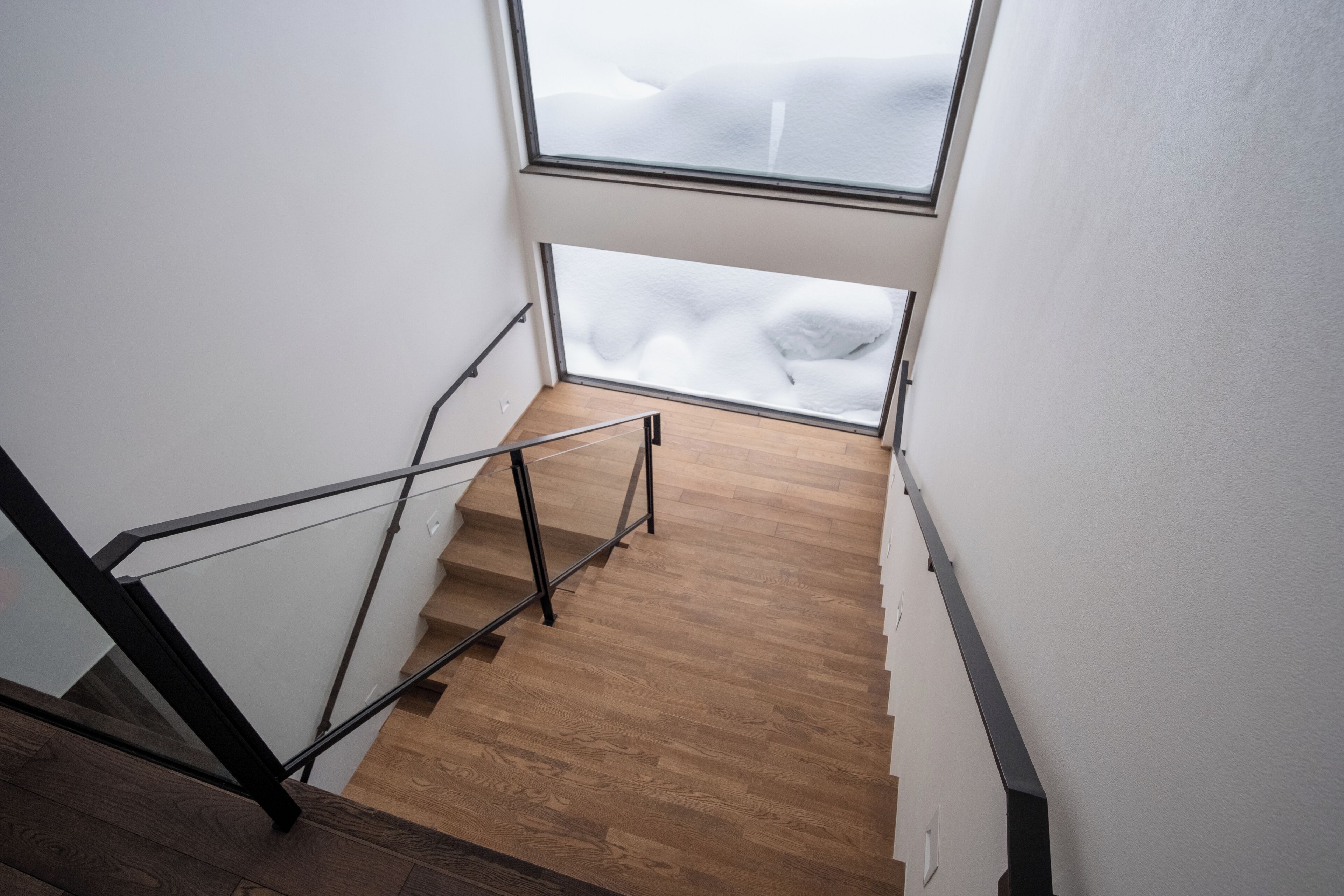 A staircase with wooden steps and metal railings leading to a room with a large window.