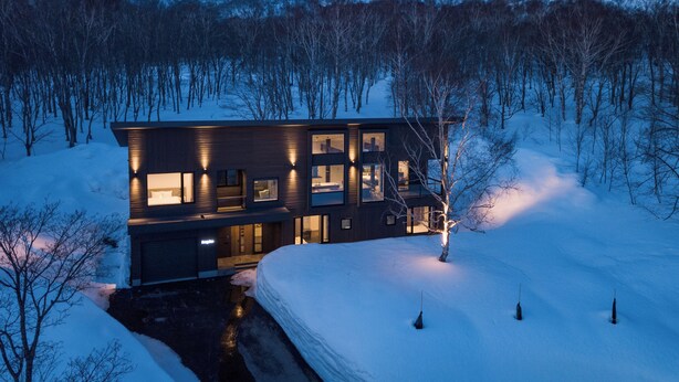 A modern two-story house with a large balcony, surrounded by snow-covered landscape and trees. - Song Saa (Niseko)