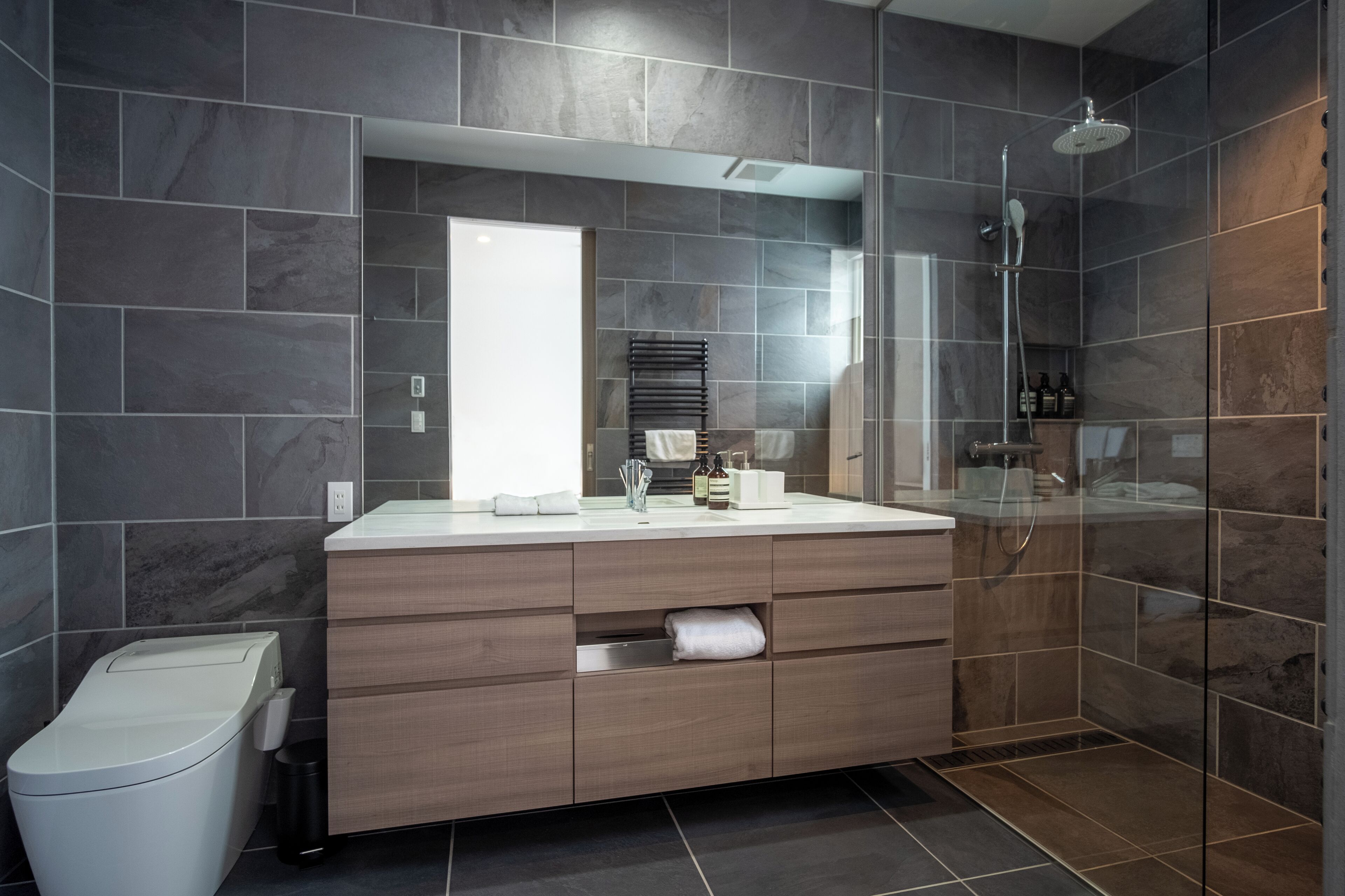 Une salle de bain moderne avec un grand miroir, une douche et des toilettes.