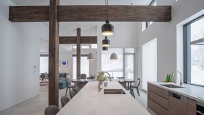 A modern kitchen with a large island, pendant lighting, and a view to the living area. - Song Saa (Niseko)