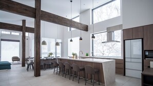 A modern kitchen with a central island, bar stools, and a large window providing natural light. - Song Saa (Niseko)