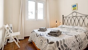 Une chambre à coucher avec un lit, une chaise, une fenêtre et un tableau au mur.