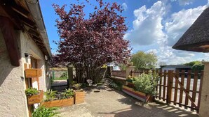 A courtyard with a tree, wooden fence, and potted plants. - Studio Apartment 'La Noisette' with Private Terrace, Private Garden and Wi-Fi (Equemauville)