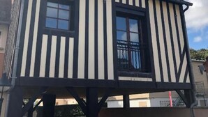 Un bâtiment à deux étages, doté d’un toit à pignon, d’un balcon et d’une fenêtre ornée d’une rambarde en métal.