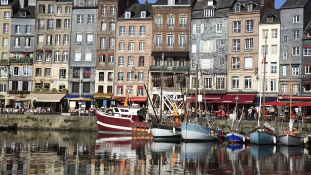 Une promenade en bord de mer, bordée de bâtiments historiques et de bateaux amarrés.