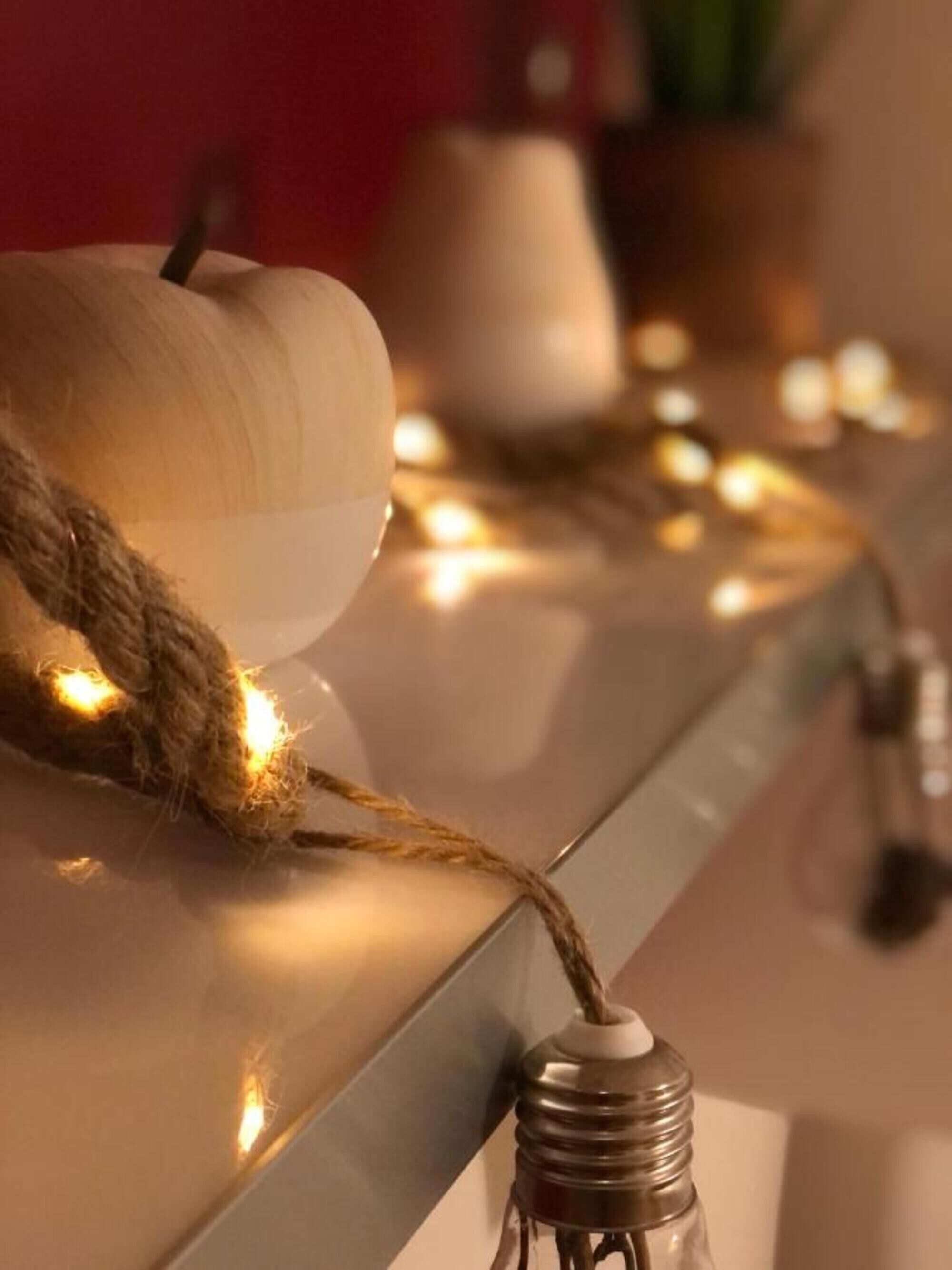 Un gros plan d’une guirlande lumineuse, avec un objet en bois et une bouteille en verre transparent.