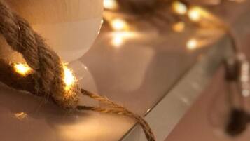 Un gros plan d’une guirlande lumineuse, avec un objet en bois et une bouteille en verre transparent.