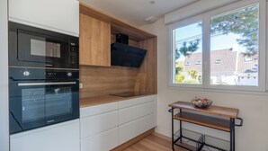 Et moderne køkken med indbyggede apparater, en træbordplade og et vindue med udsigt til huse.