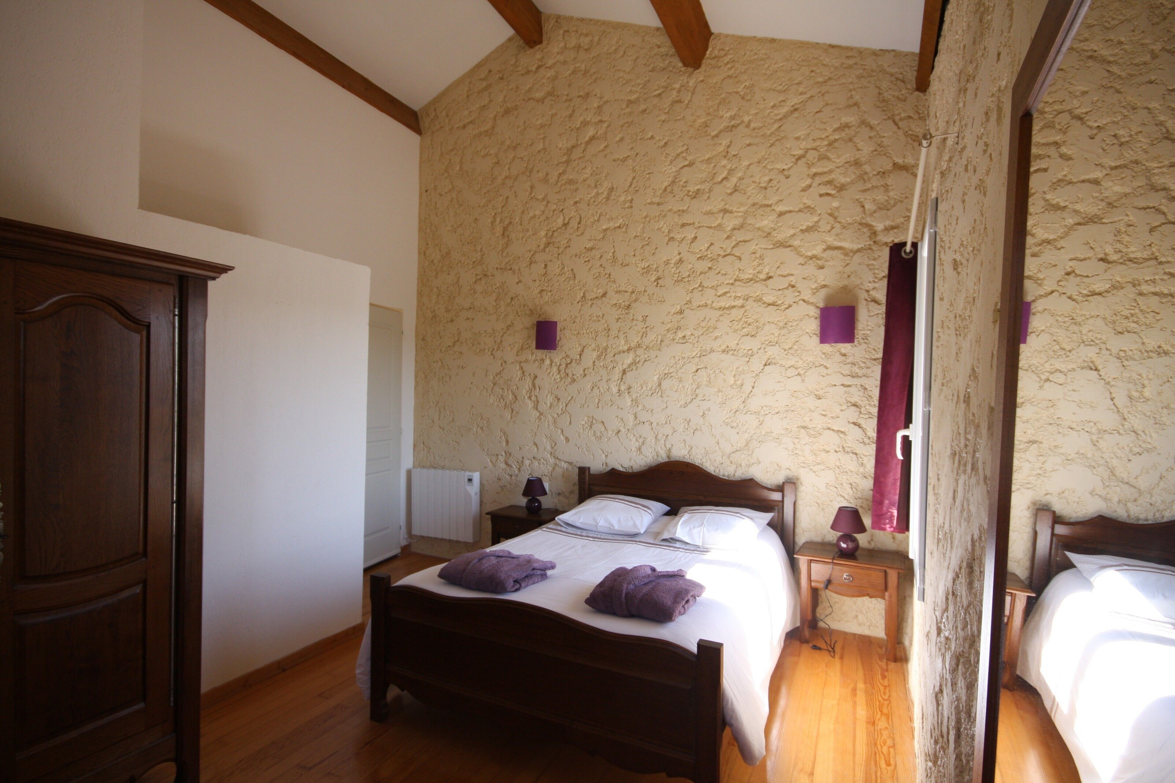A bedroom with a wooden bed, a nightstand, a mirror, and a textured wall.