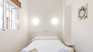 Quarto com cama, duas luminárias de cabeceira, uma janela e uma obra de arte na parede.