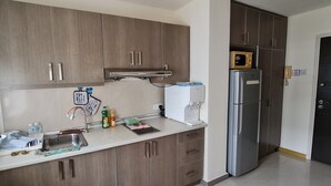 A modern kitchen with wooden cabinets, a stainless steel refrigerator, and a microwave on top.