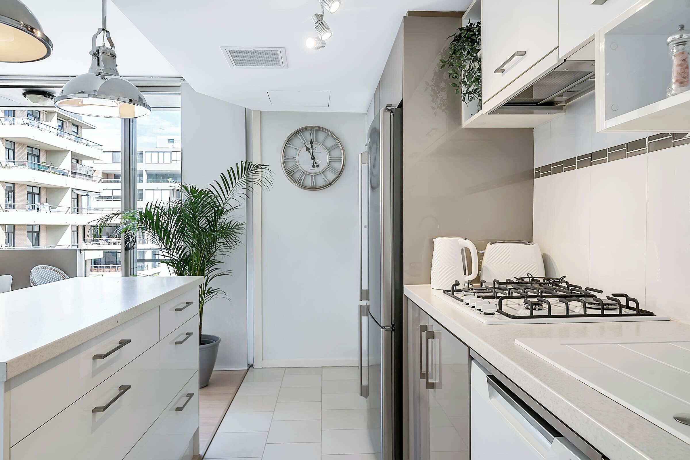 A modern kitchen with a large window, a gas stove, and a potted plant.