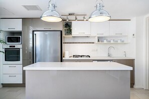 A modern kitchen with a central island, built-in oven, microwave, and stainless steel refrigerator.