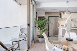 A modern kitchen with a refrigerator, stove, and dining area with a glass table and chairs.