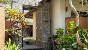A stone and wood exterior with a stone pillar and a wooden door. - Sukanami Villa Ubud by ecommerceloka (Payangan)