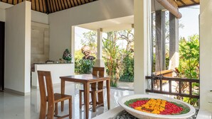 A modern interior with a dining area, a stone water feature, and a view of lush greenery outside. - Sukanami Villa Ubud by ecommerceloka (Payangan)