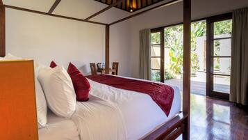 A large bed with white and red bedding, wooden headboard, and a wooden floor.