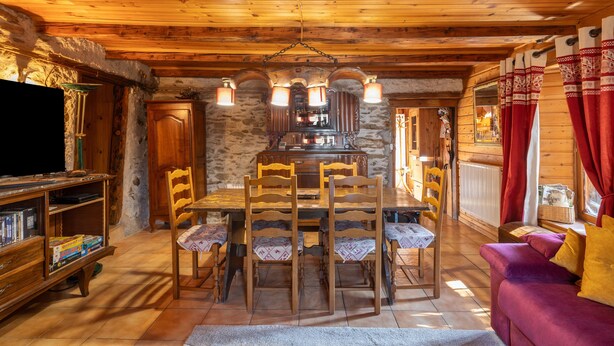 Un interno in legno con un tavolo da pranzo, sedie, un divano e una televisione.