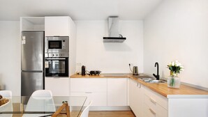 Een moderne keuken met roestvrijstalen apparatuur, een houten aanrecht en een glazen eettafel.