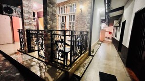 A corridor with a metal railing, stone walls, and a tiled floor. - Cosy Appartement Dans Quartier Calme à Proximité du Parc Aquatique (Kinshasa)