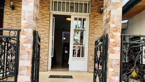 A building entrance with a stone facade, metal gates, and a tiled floor. - Cosy Appartement Dans Quartier Calme à Proximité du Parc Aquatique (Kinshasa)