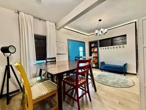 A dining area with a wooden table, chairs, a floor lamp, and a blue sofa.