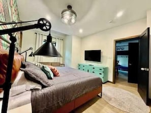 A bedroom with a bed, a desk, a chair, a TV, and a wardrobe.