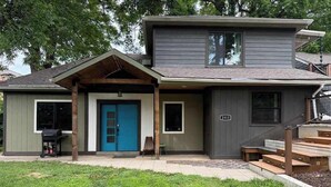 Une maison à deux étages avec une porte d’entrée bleue, un petit porche et le numéro « 2313 » sur le côté.