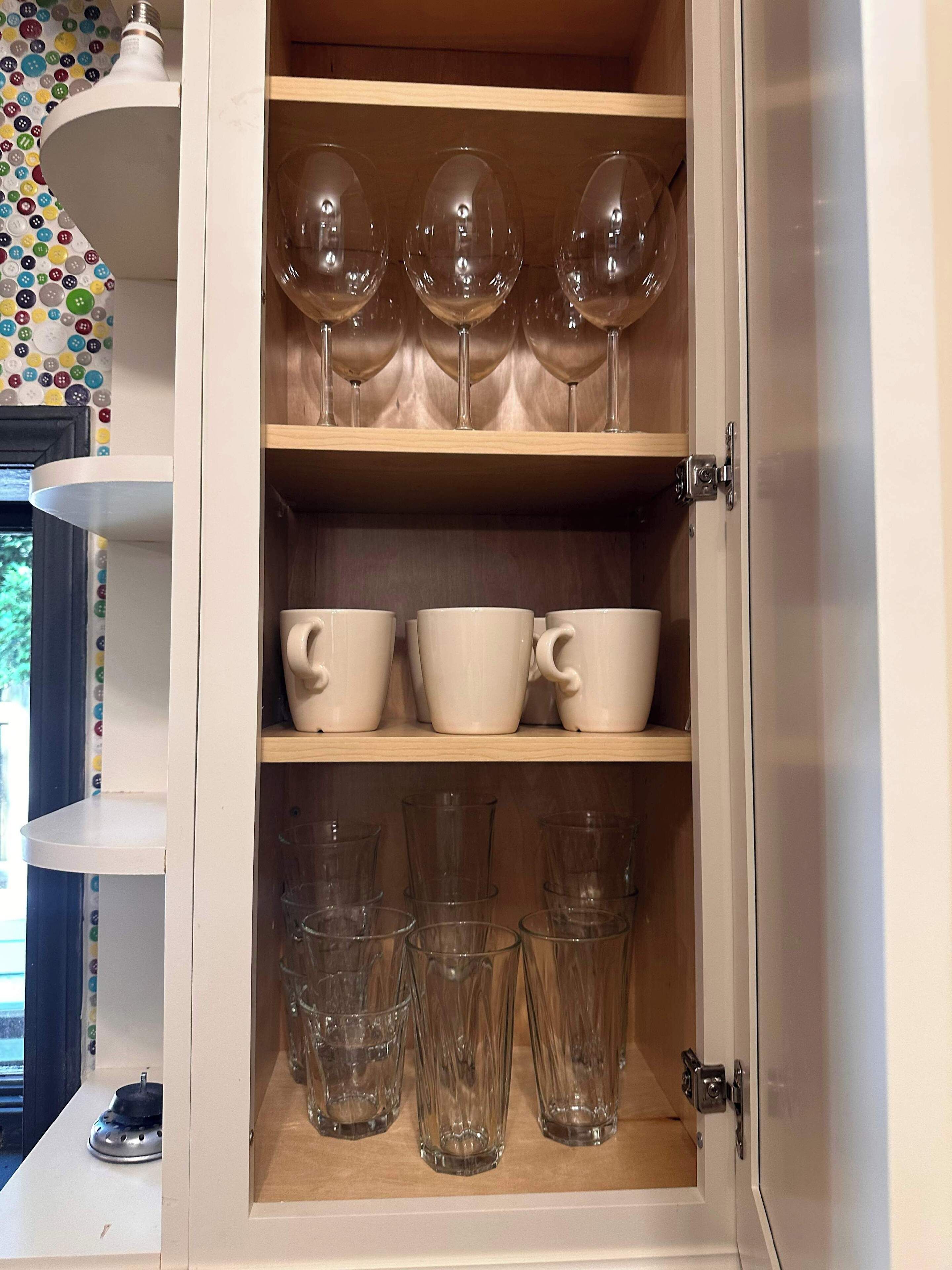 Ein Schrank mit Regalen für Weingläser, Tassen und Gläser.