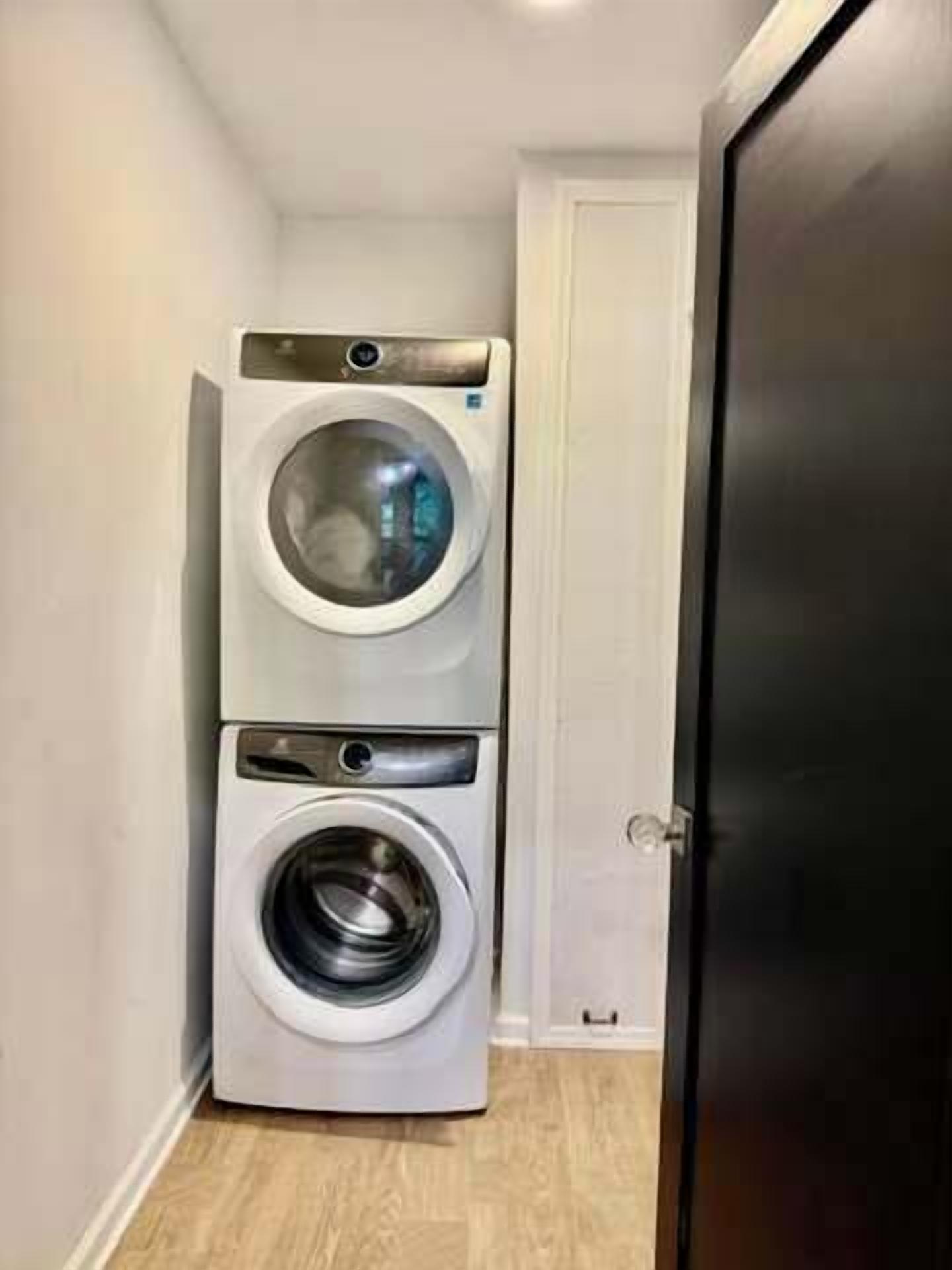 A laundry room with stacked washing machines and a door.