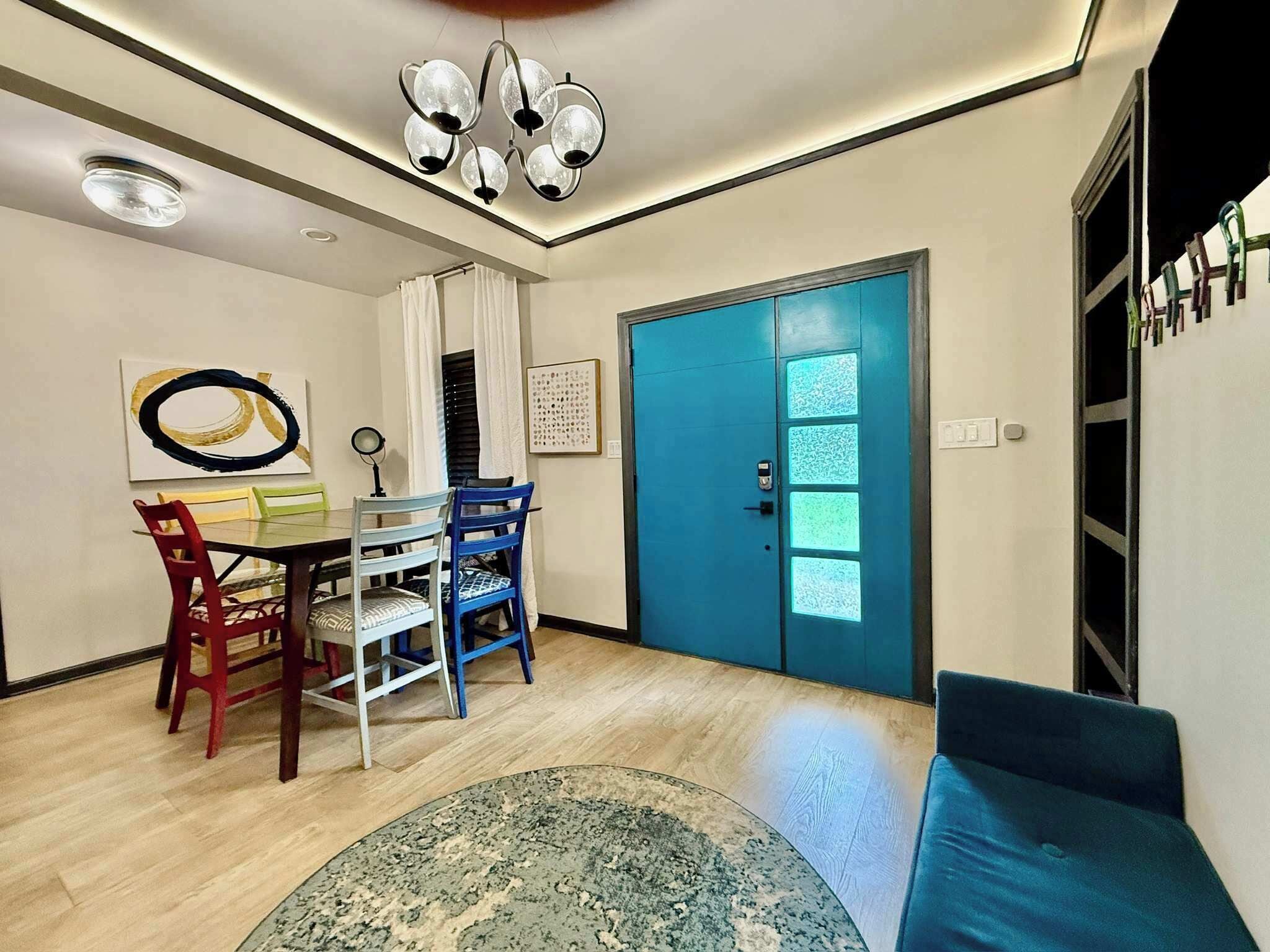 A dining area with a table and chairs, a blue door, and a ceiling light fixture.