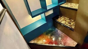 Un intérieur moderne avec des motifs géométriques sur les murs, un sol métallique et une présentation de divers objets.