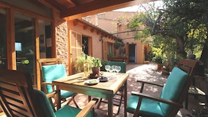 Une terrasse extérieure avec des meubles en bois, une table dressée avec des assiettes, des verres et une plante en pot.