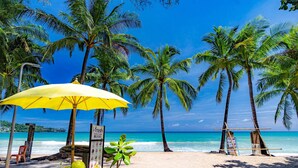 A beach with a yellow umbrella, palm trees, and coconuts. - Citygate Kamala Residence P602 (Kamala)