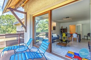 A modern interior with a balcony, a dining area, and a living room with a sofa and chairs. - Clos Jean – T3 Apartment | Perfect for Families (Menthon-Saint-Bernard)
