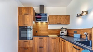 A modern kitchen with wooden cabinets, a built-in oven, a microwave, and a coffee maker.